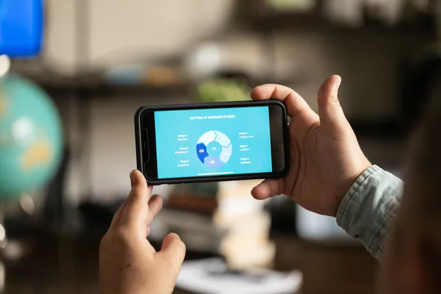 Close-up of hands holding a smartphone displaying a business chart indoors. Campaign measurement practices: the metric contract to write before launch