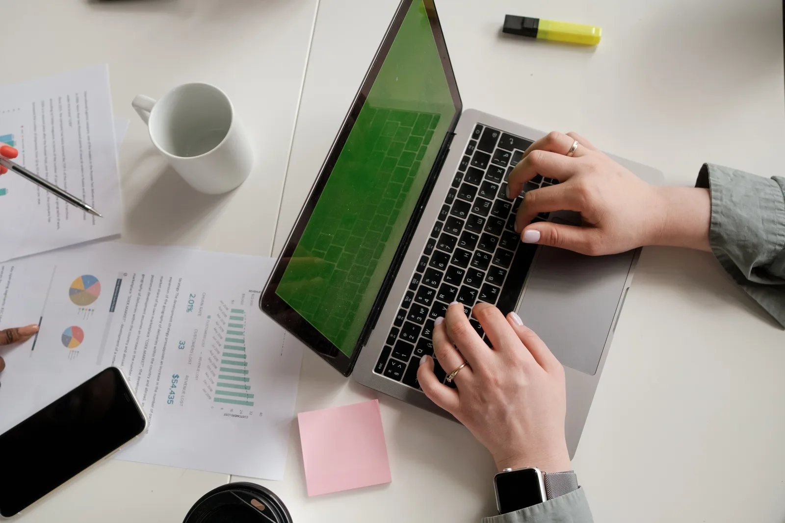 Modern office desk setup with a laptop, papers, and hands typing. Campaign measurement tools: how to split a report