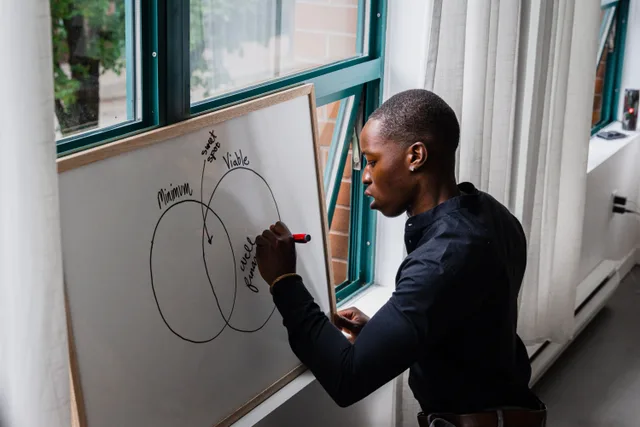 African American man writing on whiteboard with Venn diagram, indoors. Marketing analytics strategy questions with honest answers attached