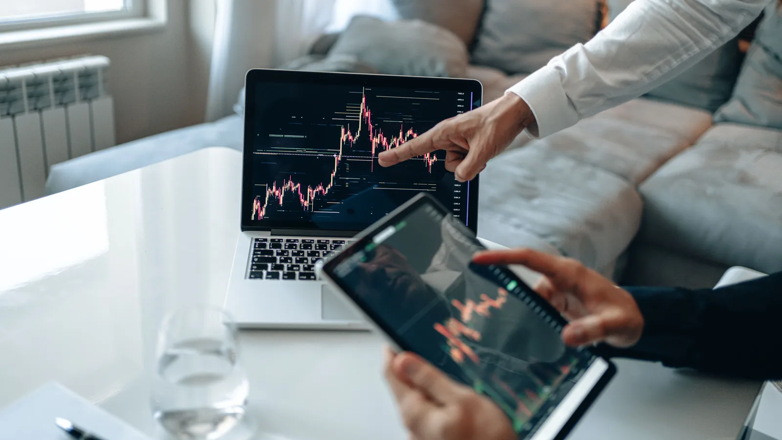 Hands analyzing stock market trends on laptop and tablet, indoors setting. The marketing mix modeling questions worth asking before anything else