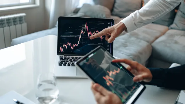 Hands analyzing stock market trends on laptop and tablet, indoors setting. The marketing mix modeling questions worth asking before anything else