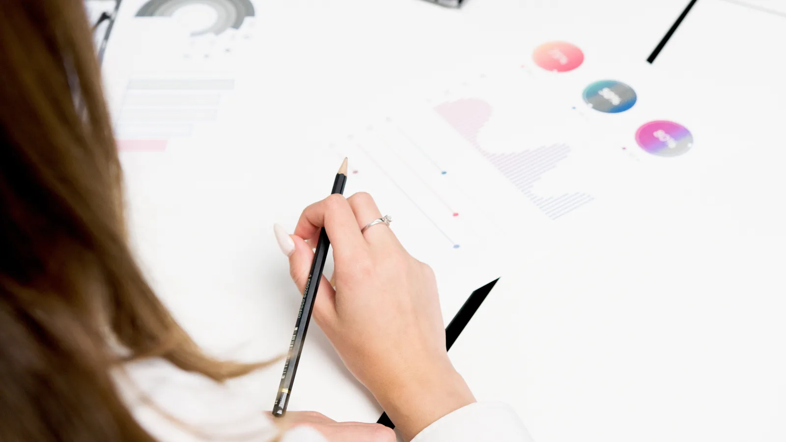 A woman reviews colorful financial charts with a pencil, focusing on growth and data analysis. Google Analytics 4 attribution models in 2027: what US teams must know