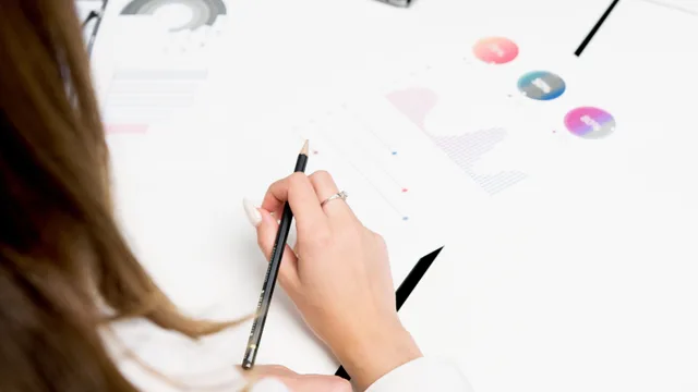 A woman reviews colorful financial charts with a pencil, focusing on growth and data analysis. Google Analytics 4 attribution models in 2027: what US teams must know