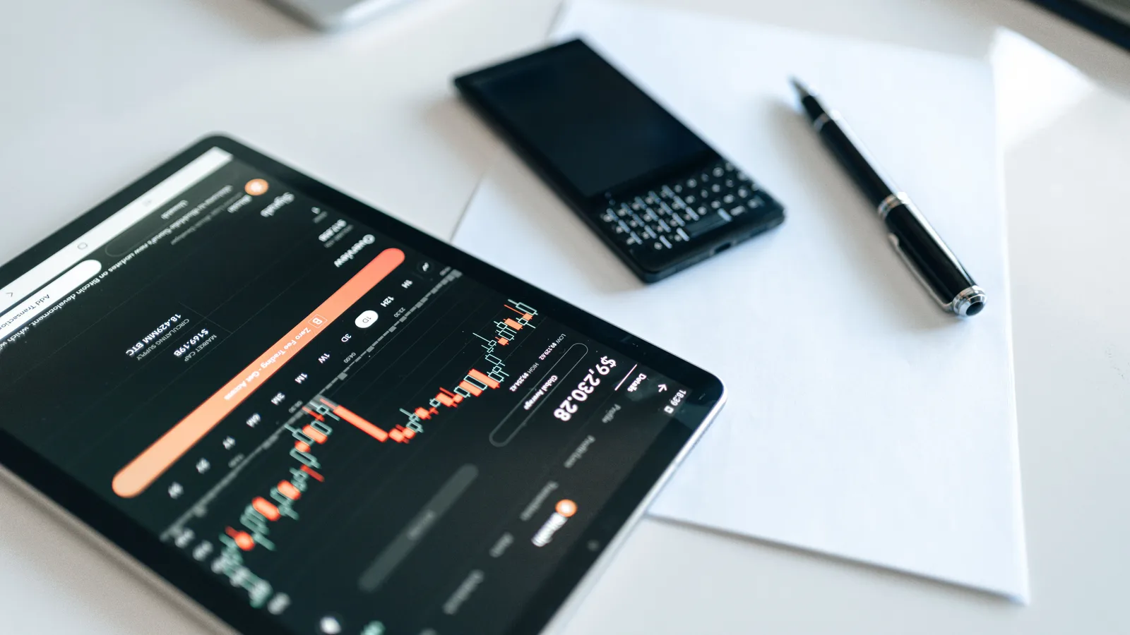 Close-up of a tablet displaying financial charts with a phone and pen on a white surface. Measuring marketing mix modeling: a staged scorecard with six gates
