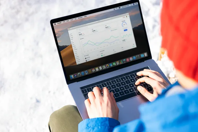 A person in a blue jacket analyzing business analytics on a laptop outdoors during winter. Marketing mix modeling benchmarks: baselines, ranges and outliers